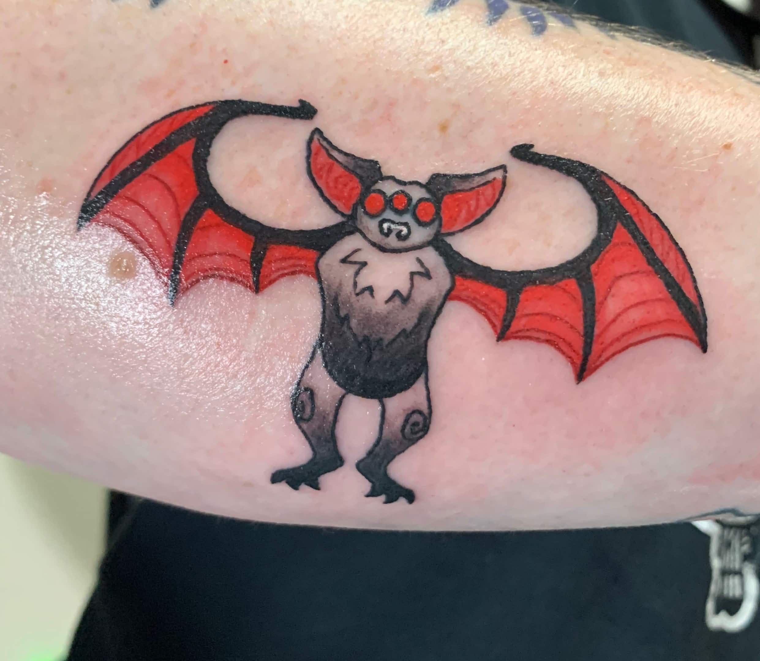 tattoo of a bat with red eyes, ears, and wings